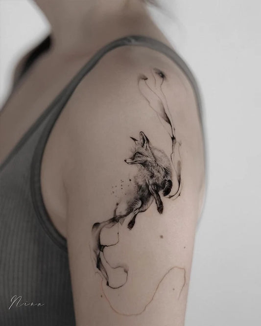 black watercolor brush stroke abstract fox tattoo on woman upper arm