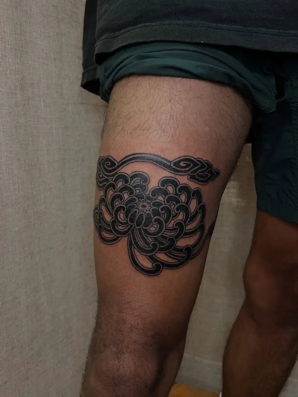japanese blackwork lotus flower tattoo on man thigh above knee