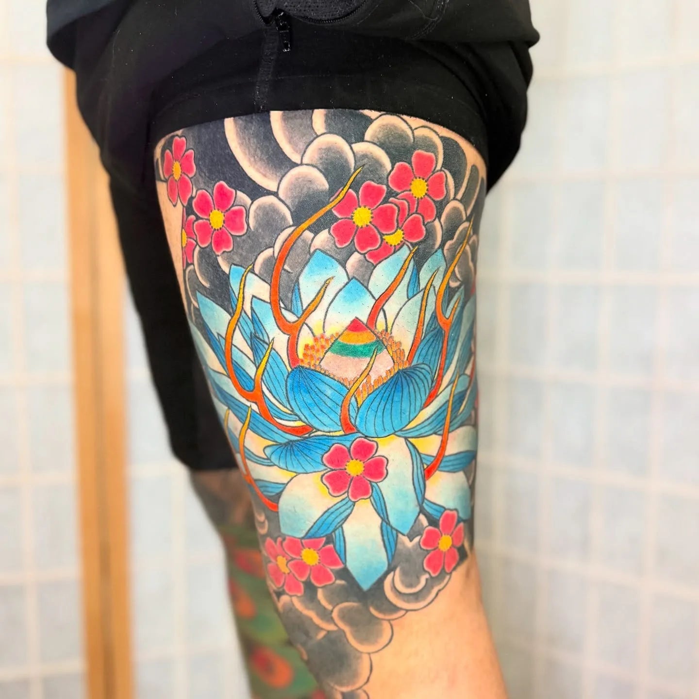 colorful japanese lotus flower tattoo on man thigh half sleeve
