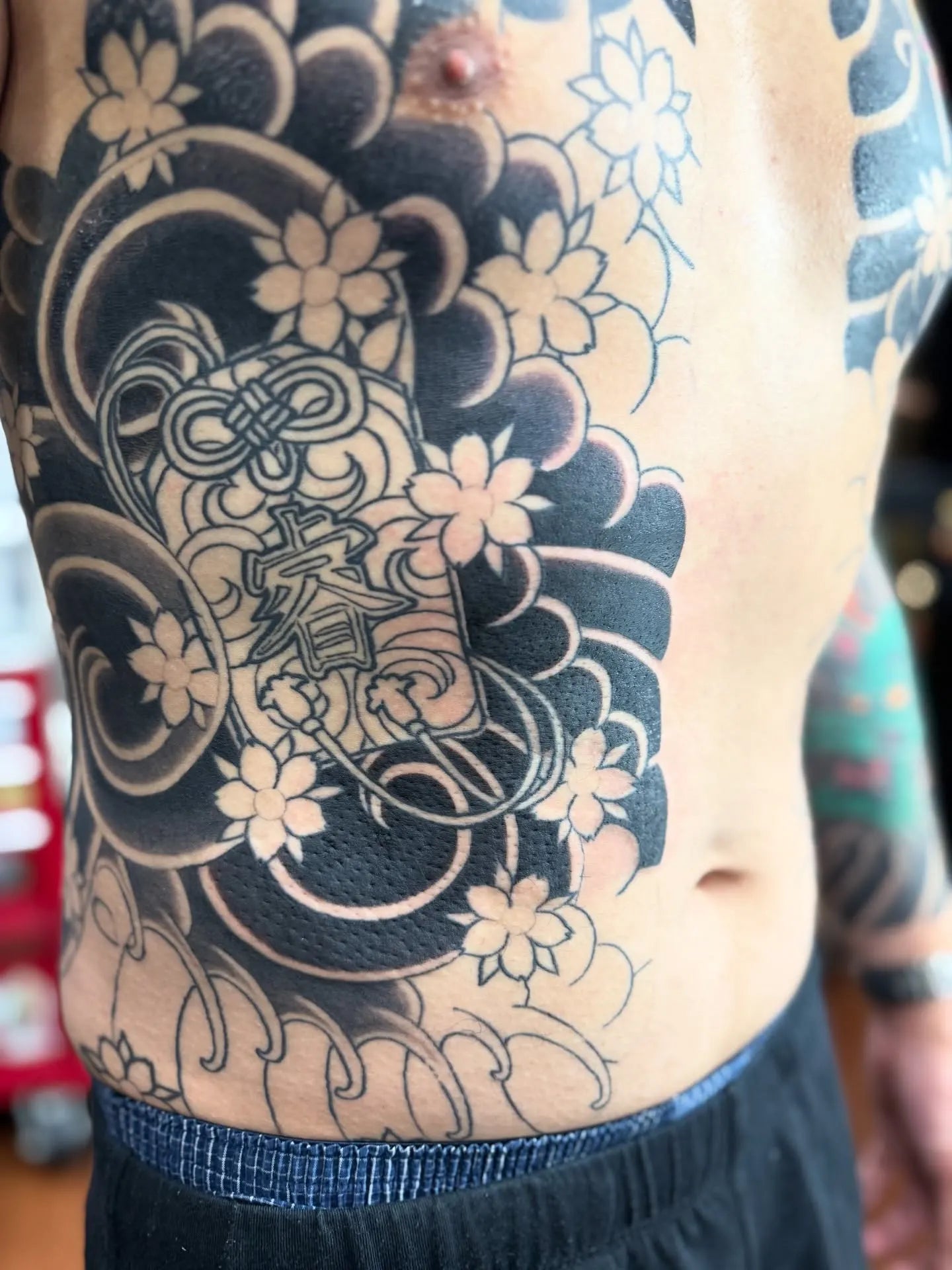 black japanese tattoo with flowers on man rib