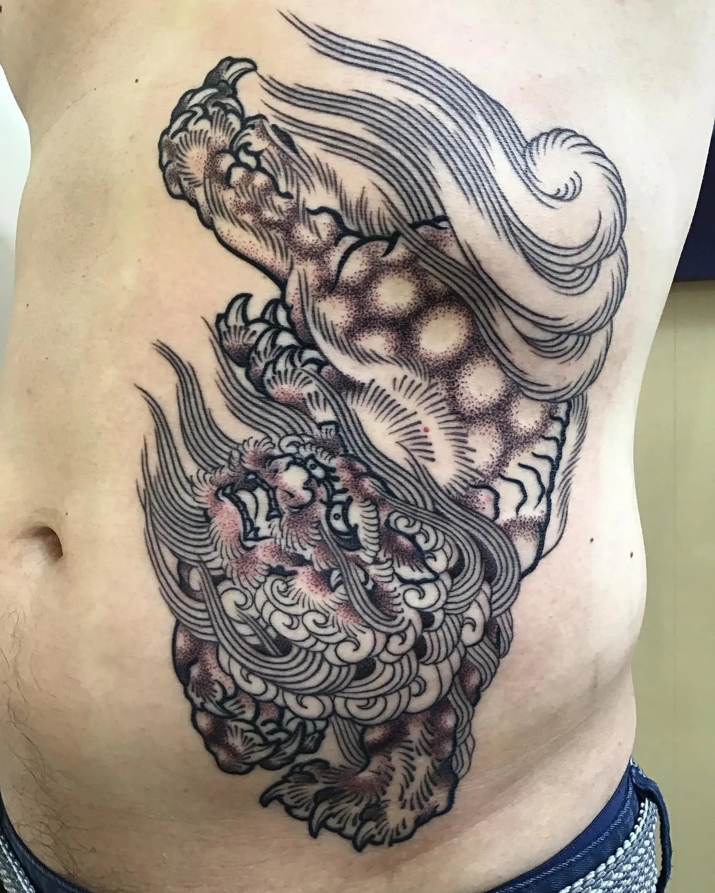 japanese abstract wave tattoo on man rib stomach