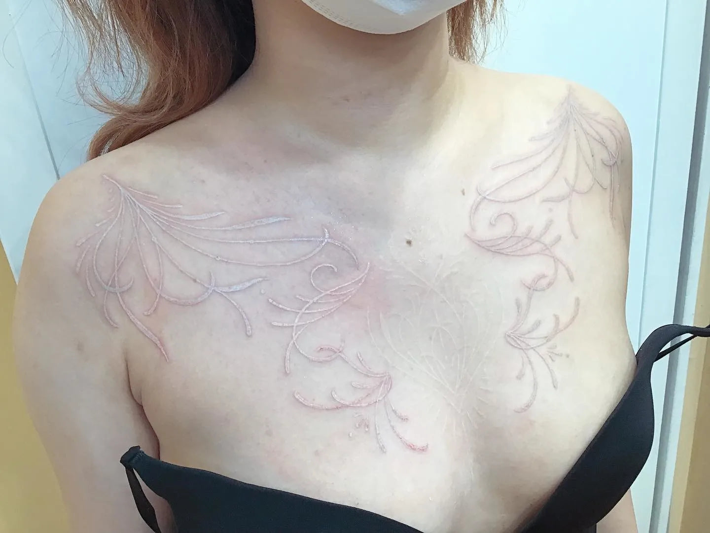 floral fine line white ink tattoo on woman chest and shoulder