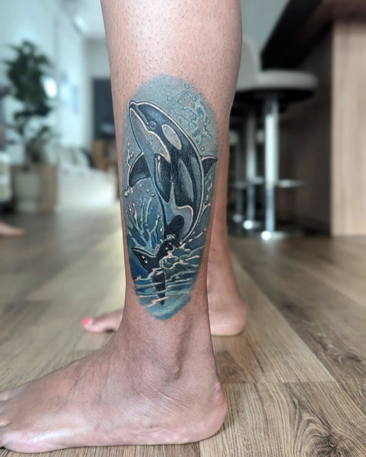 Orca whale tattoo color realism on leg ankle