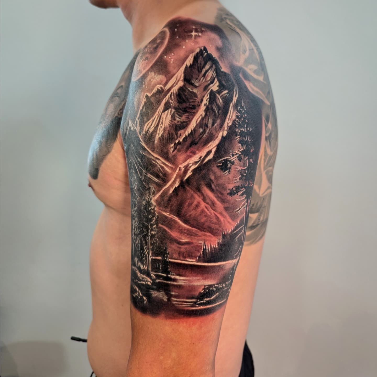 black and grey realism mountain landscape tattoo on man upper arm half sleeve