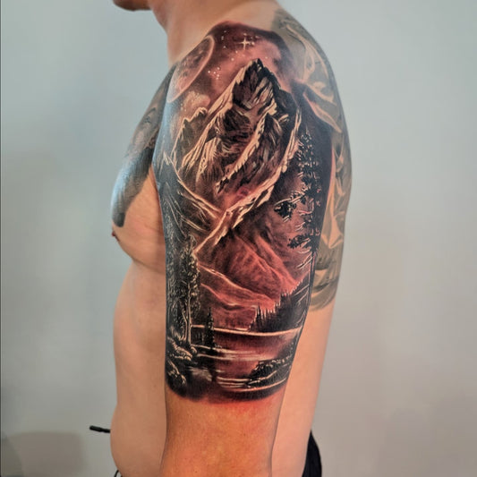 black and grey realism mountain landscape tattoo on man upper arm half sleeve