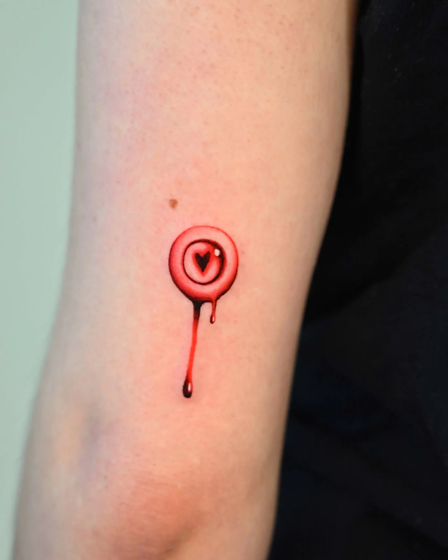 red dripping circled heart upper arm tattoo