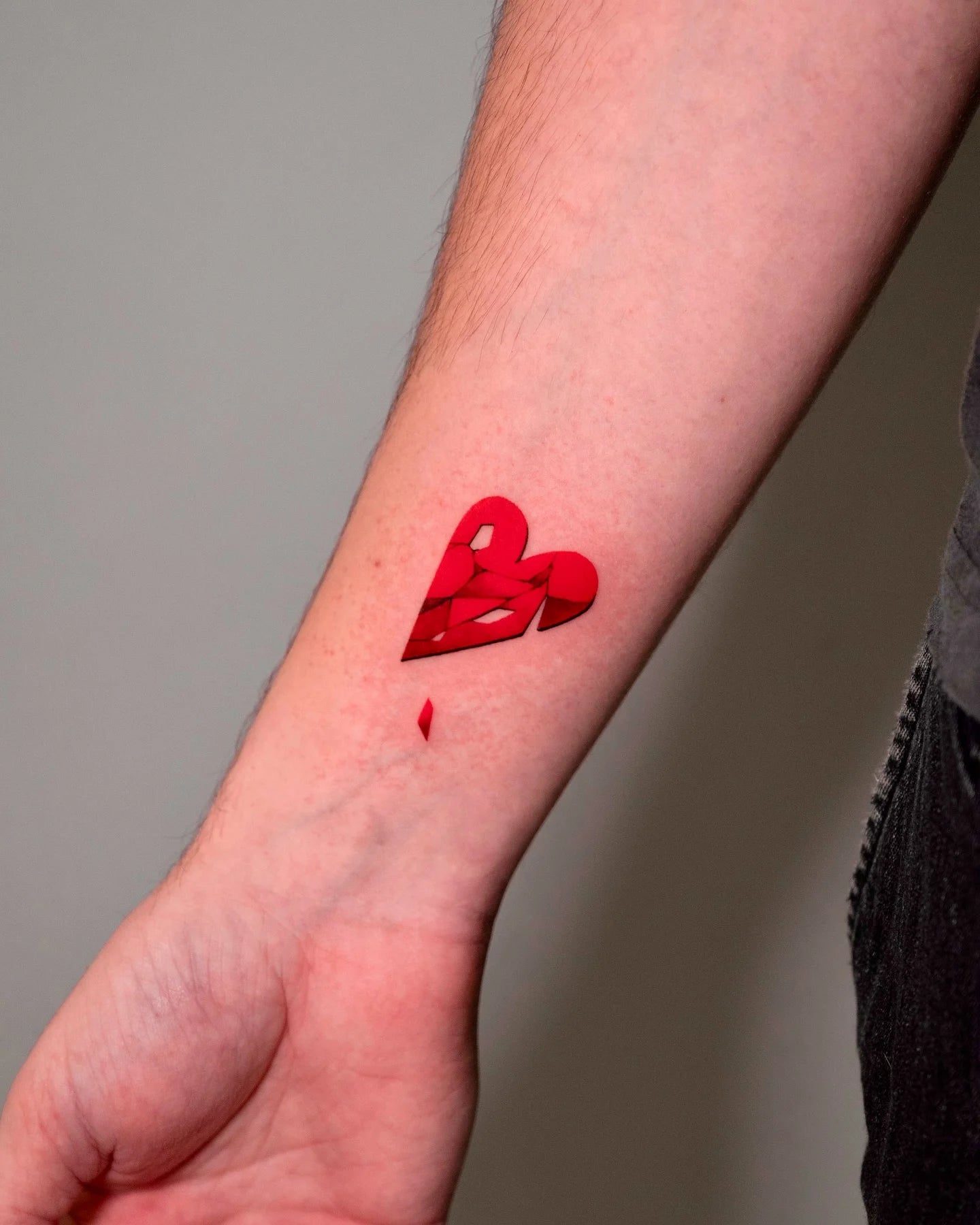 broken red heart wrist tattoo