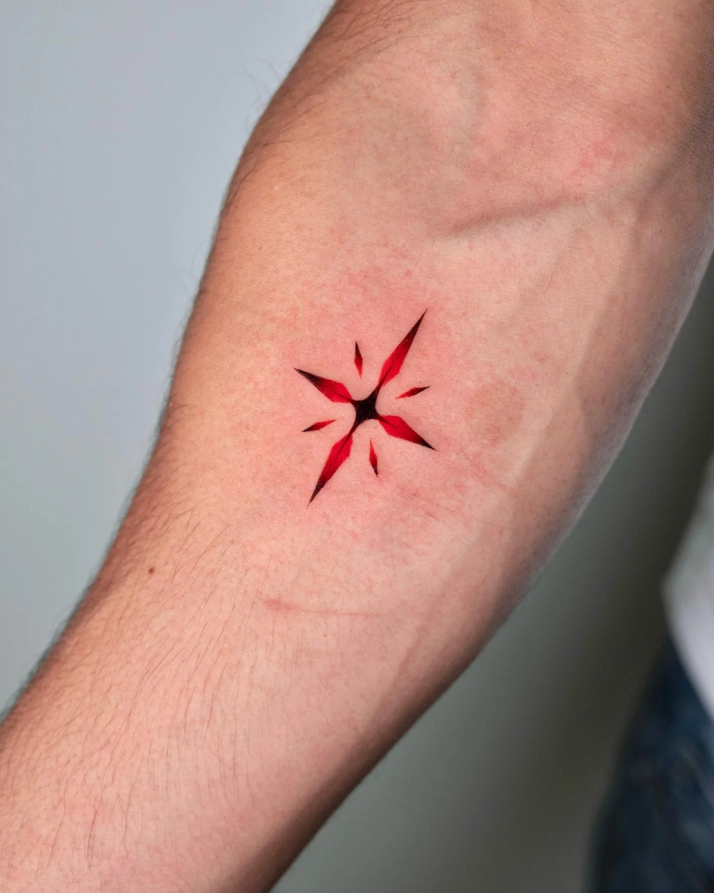 red and black star cross forearm tattoo