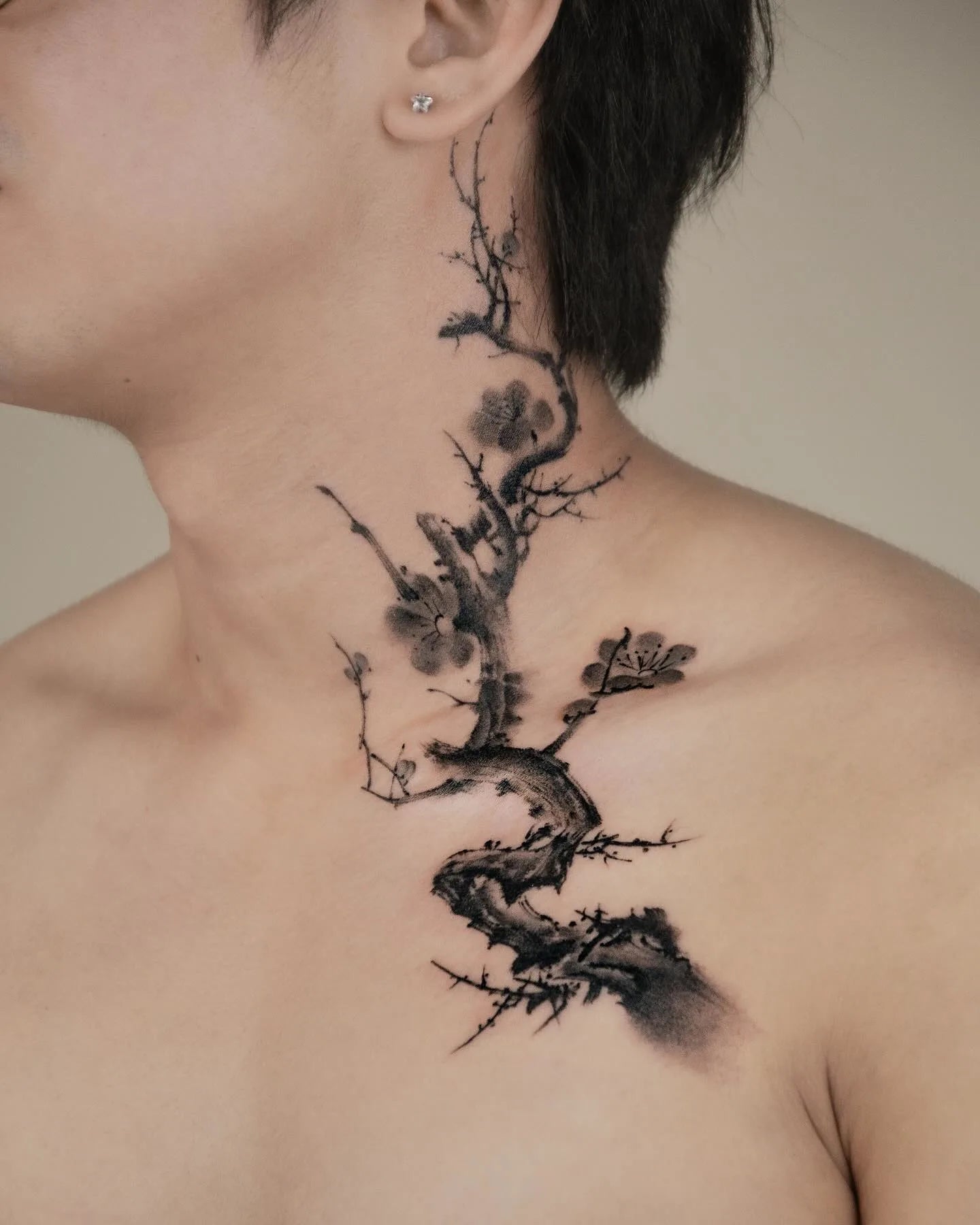 chinese black watercolor Tattoo of a tree branch design on a person's neck and shoulder