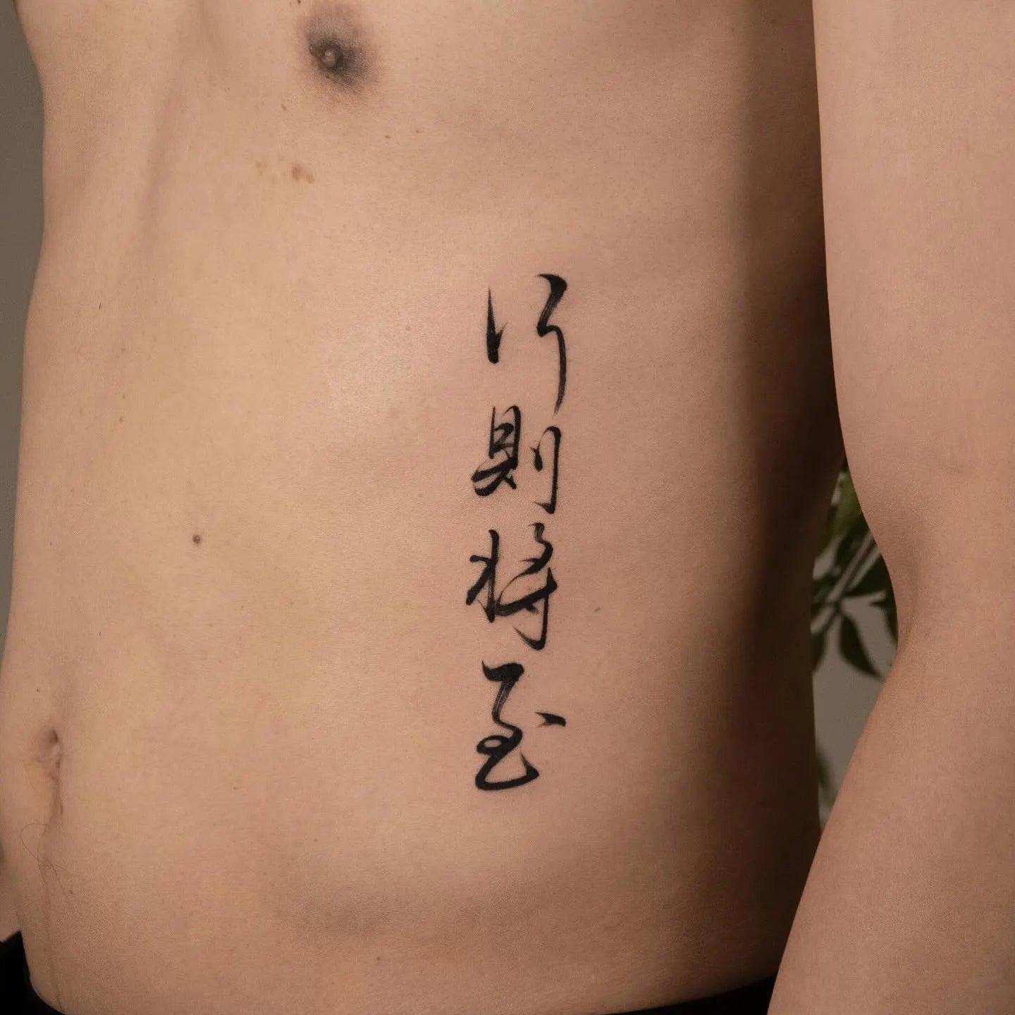 brush stroke chinese calligraphy lettering tattoo on man rib