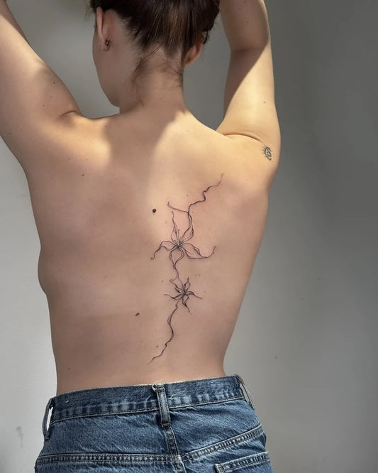 fine line flower woman back tattoo