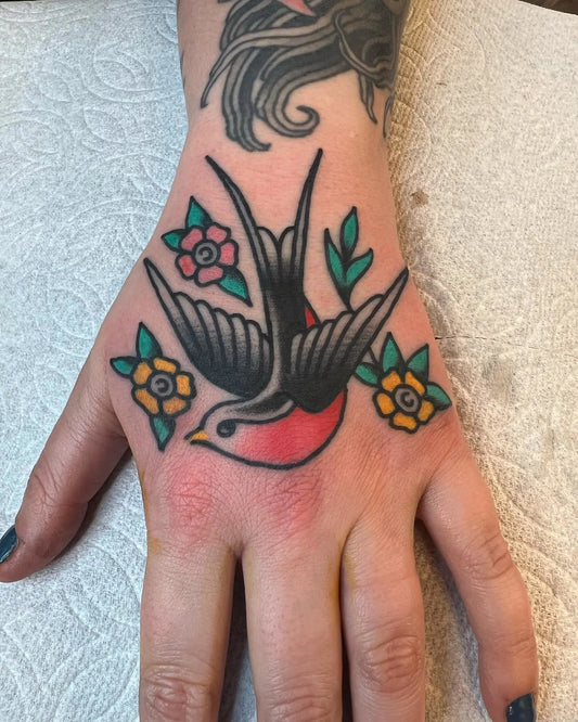 Hand with a tattoo of a swallow and flowers