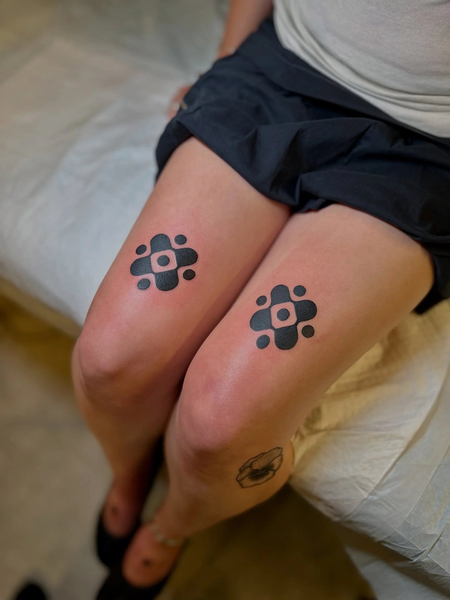 matching blackwork floral cross shape tattoo on woman thigh