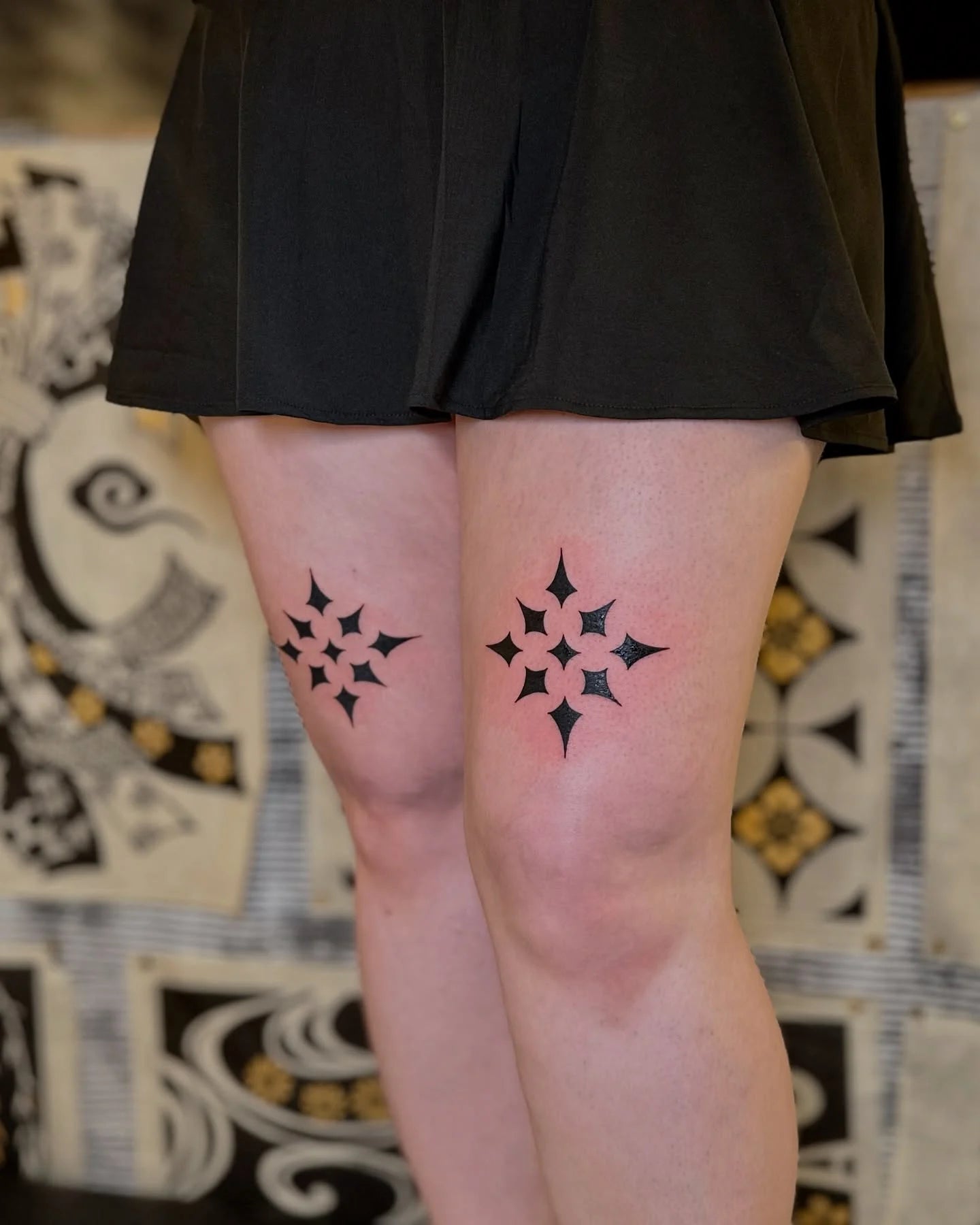matching blackwork star shaped patterns tattoo on woman thighs