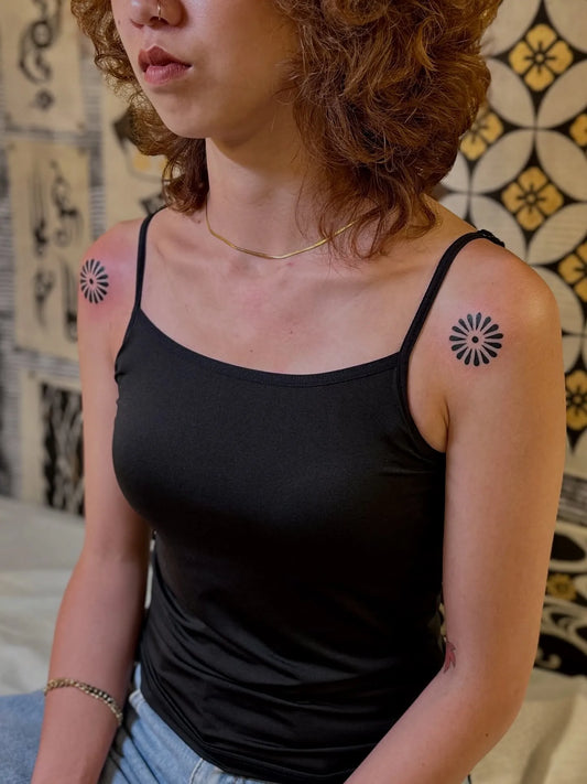 matching blackwork circle pattern tattoos on woman shoulder