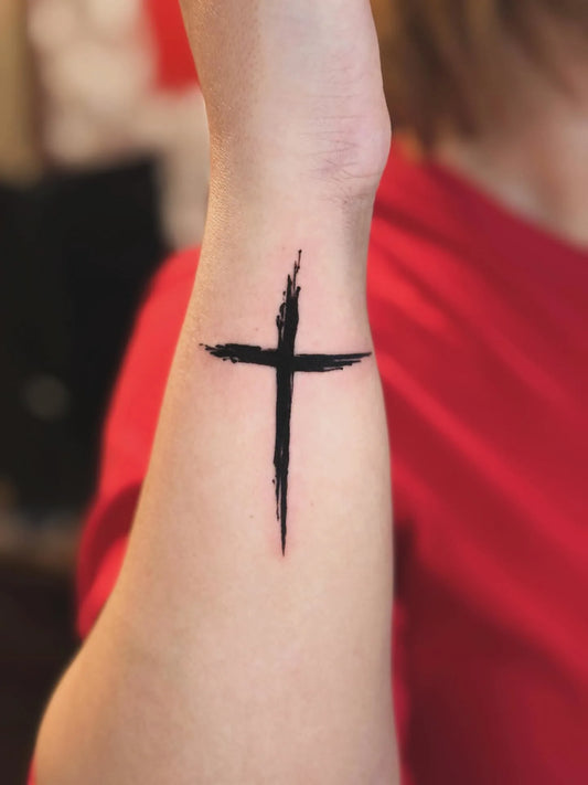 minimalist black cross sketch tattoo on wrist