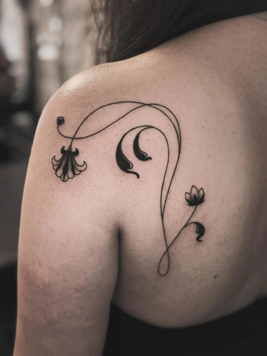 Black floral tattoo on woman back shoulder