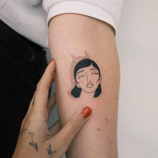 abstract woman face with devil horns shadow tattoo on forearm