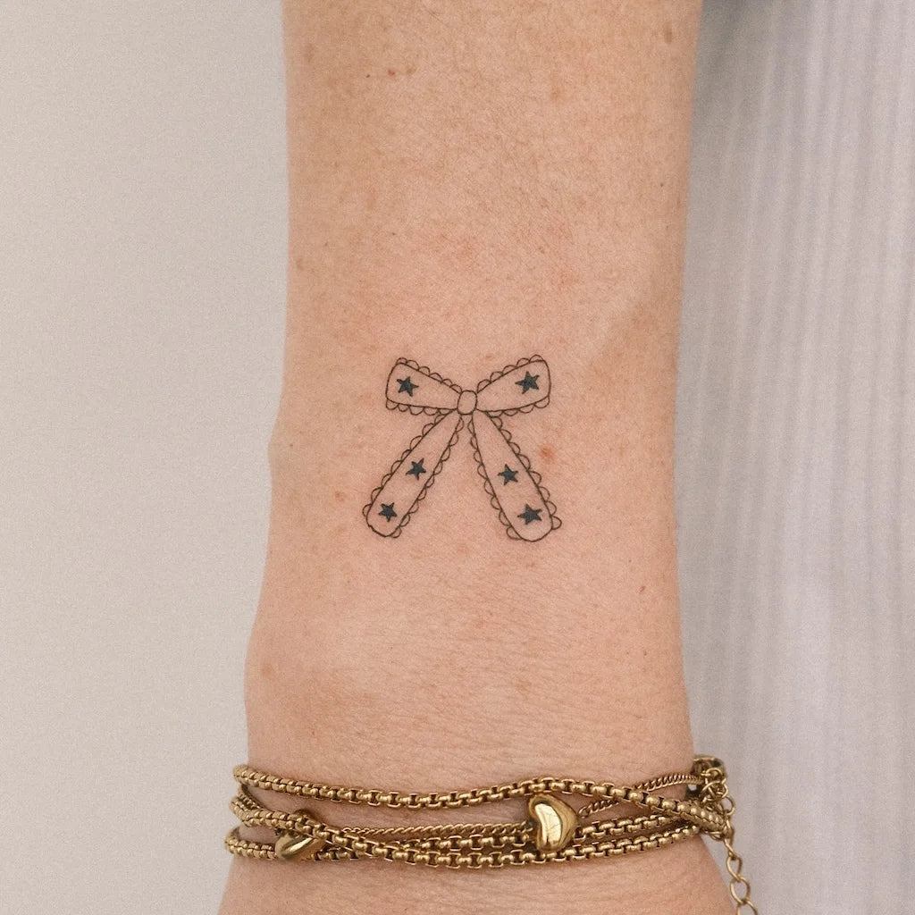 minimalist fine line bowtie outline tattoo on wrist