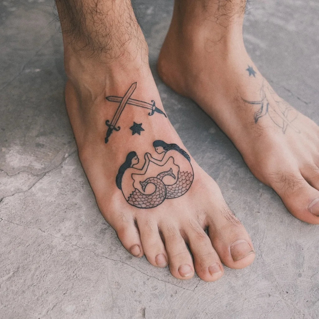 Tattoo of a mermaid and sword on a foot