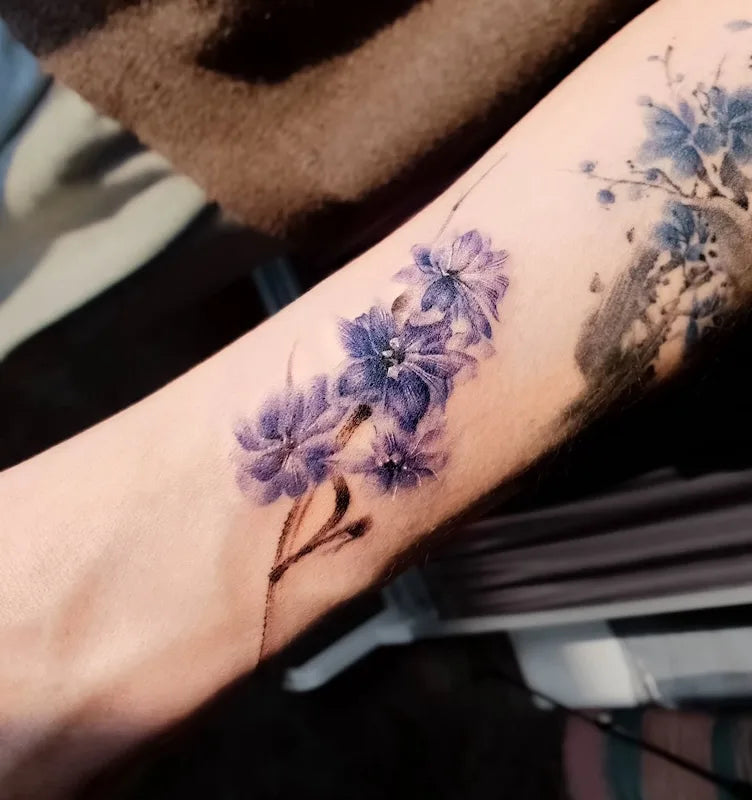 purple floral watercolor tattoo on forearm