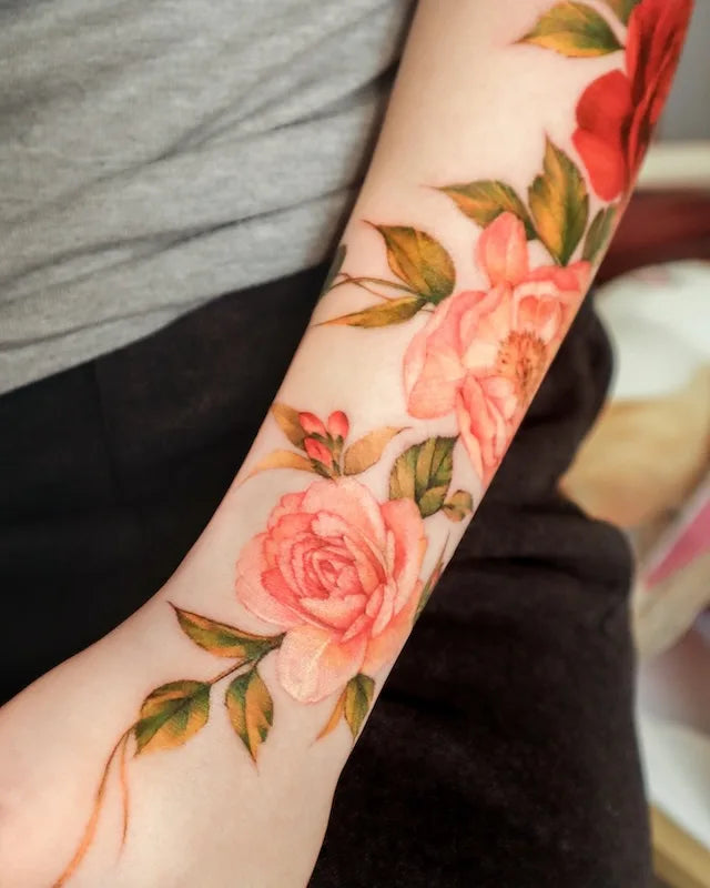 colorful realistic pink floral tattoo on woman forearm
