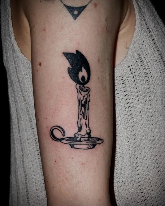 black and white traditional candle illustrative tattoo on woman upper arm