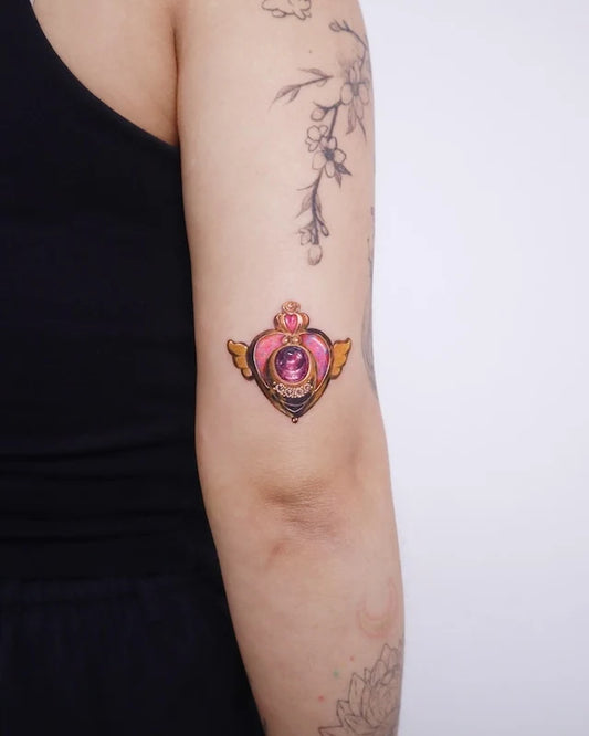 heart-shaped gemstone color realism tattoo on upper elbow