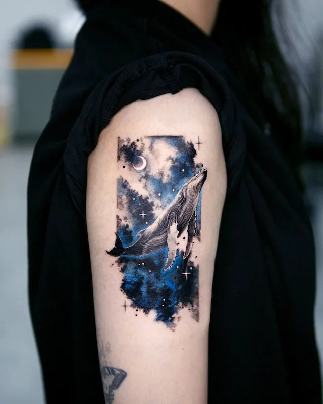 dark blue orca whale starry sky color realism tattoo on woman upper arm