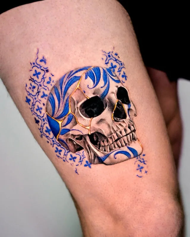 blue gold ceramic porcelain skull color realism tattoo on woman thigh