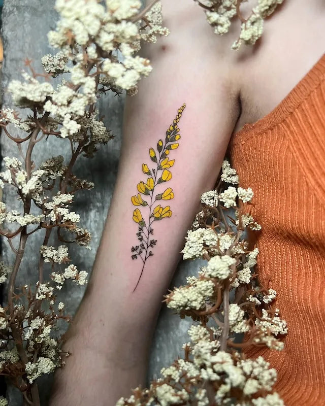 yellow flower tattoo on woman bicep