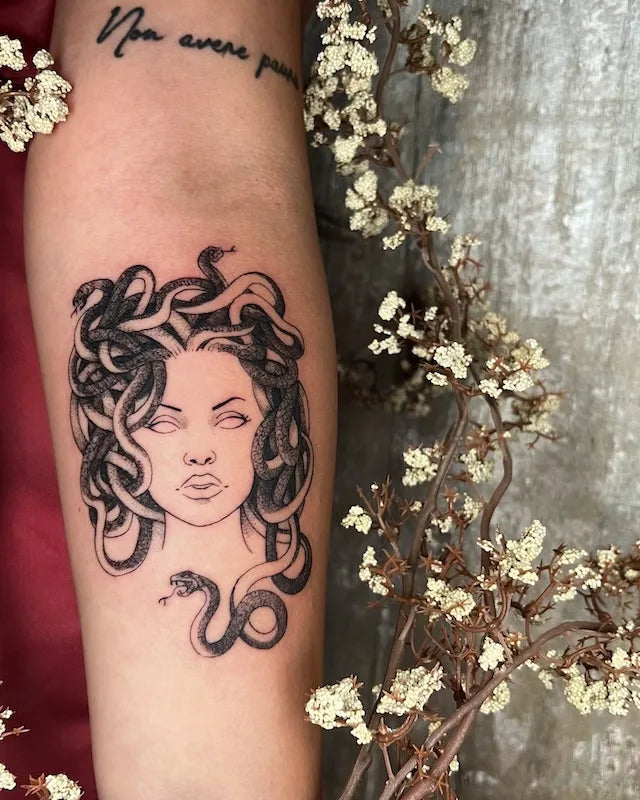 black and grey medusa tattoo on woman inner forearm