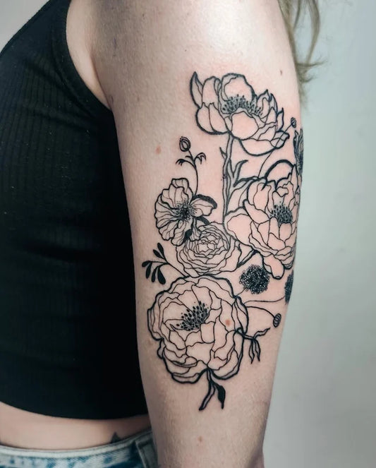bold blackwork lines floral tattoo on woman upper arm