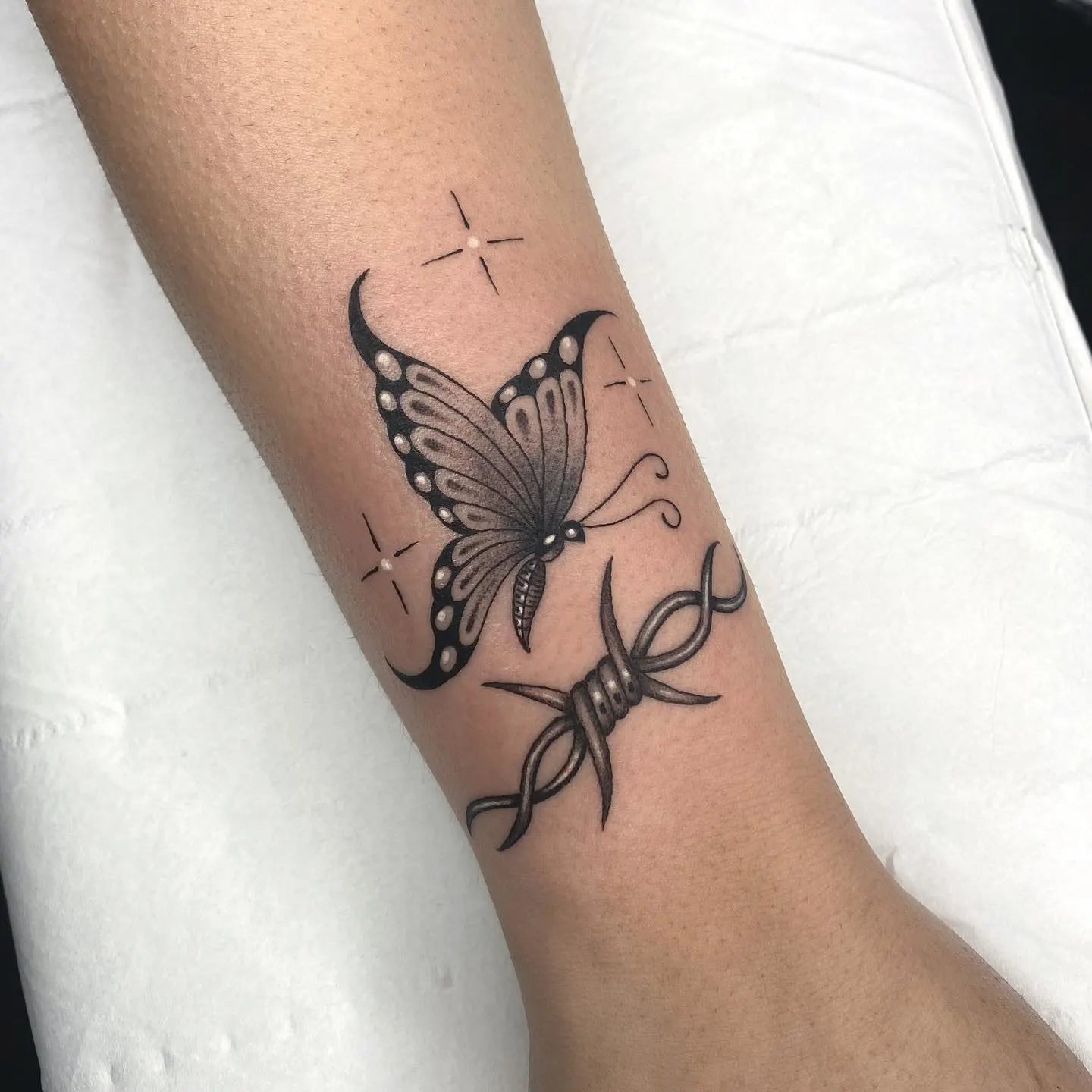 shining butterfly and barbed wire tattoo on woman wrist