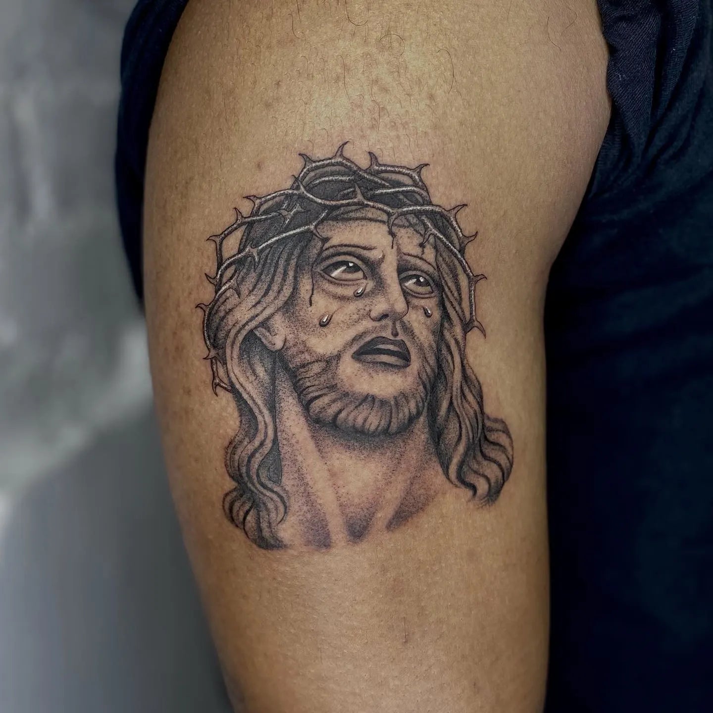 black and grey Jesus with tears tattoo on man upper arm