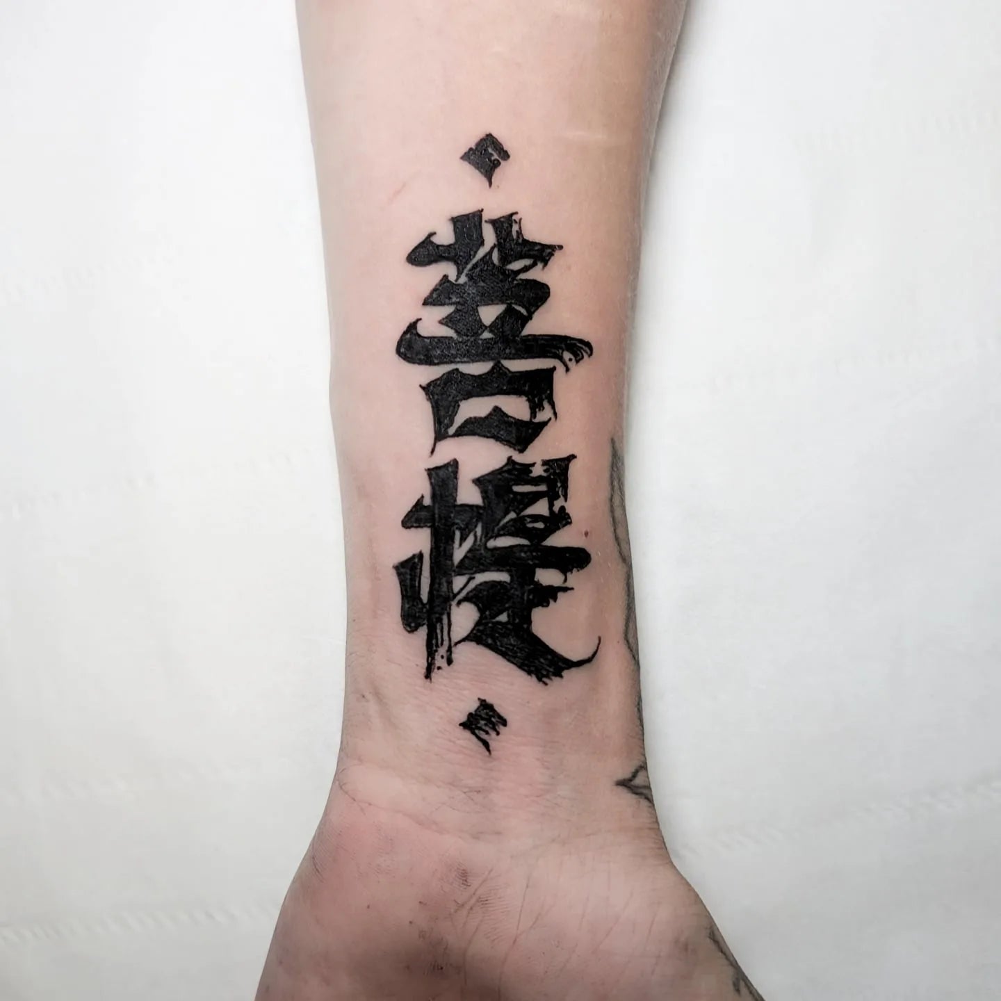 blackwork chinese bold lettering tattoo on man wrist