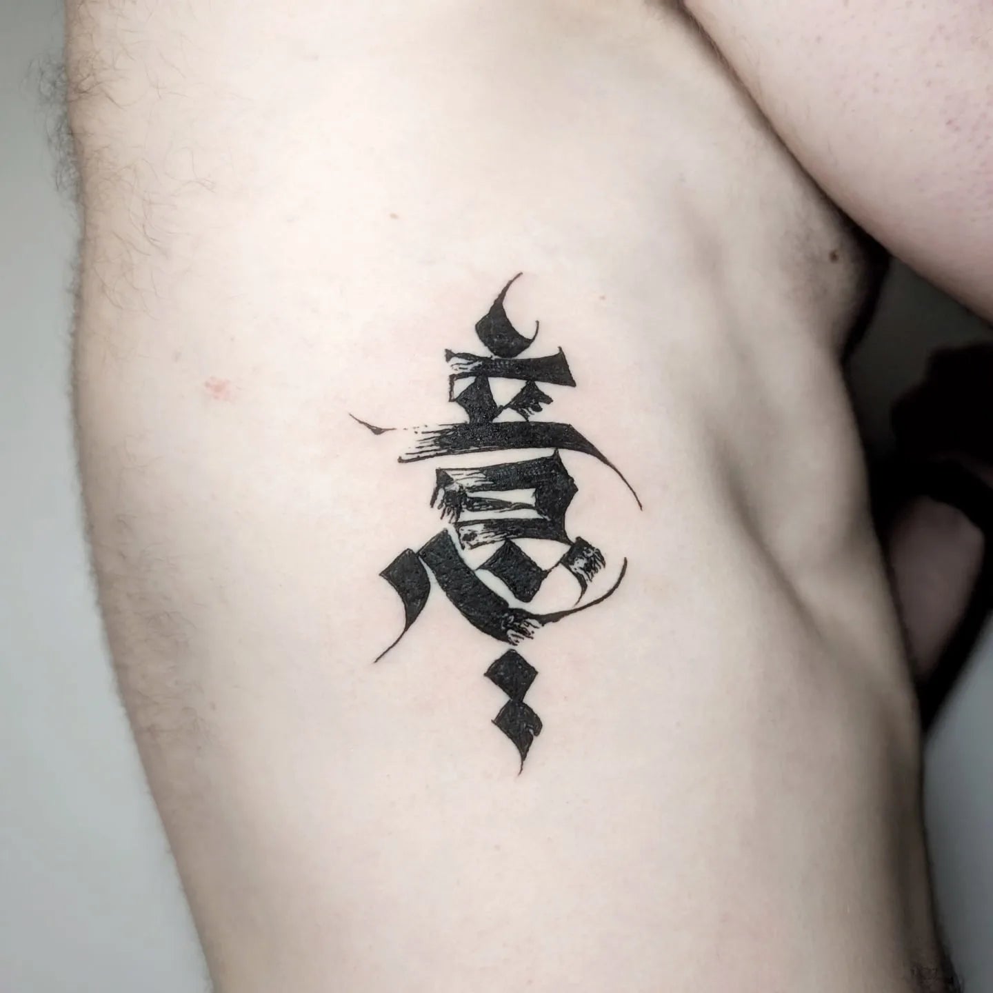 blackwork chinese lettering tattoo on man rib