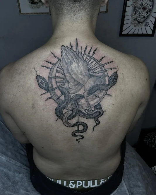 black and grey praying hands with snake tattoo on man back