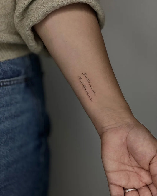 minimalist lettering wrist tattoo