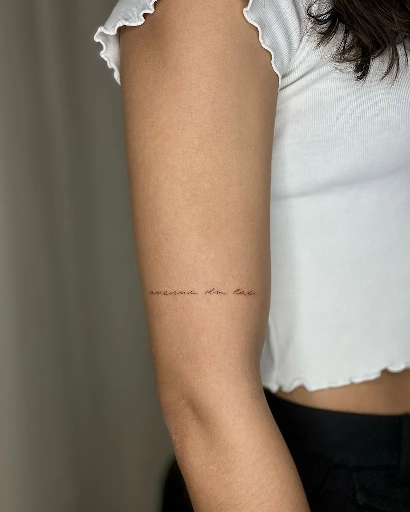 minimalist lettering upper arm wrap tattoo