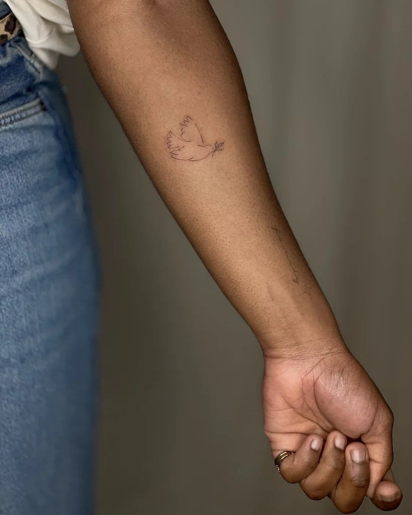 minimalist bird outline forearm tattoo