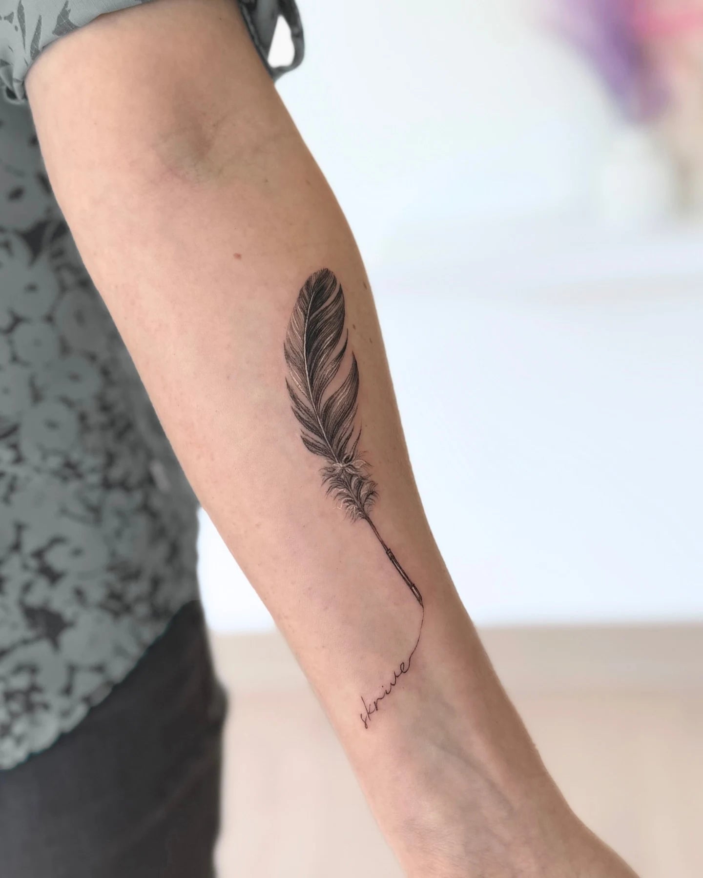 feather lettering fine line forearm tattoo